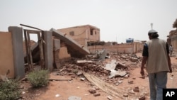 FILE —A man walks by a house hit in recent fighting in Khartoum, Sudan, Tuesday, April 25, 2023. 