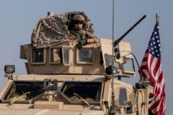 FILE - A U.S. military convoy drives near the town of Qamishli, Syria, Oct. 26. 2019. Two successful raids by the U.S.-led coalition in the oil-rich Deir el-Zour area were highlighted with the capture of a mid-level Islamic State leader.