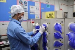 FILE - A worker inspects newly-made gloves at Top Glove factory in Klang, Malaysia, March 3, 2020.