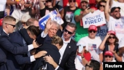 FILE - Calon presiden dari Partai Republik dan mantan Presiden AS Donald Trump melambaikan tangan dengan wajah berlumuran darah saat dibantu oleh personel Dinas Rahasia AS setelah tertembak saat kampanye di Butler Farm Show, Pennsylvania, 13 Juli 2024. (Brendan McDermid/REUTERS)