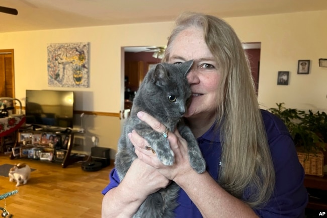 Juanita Mengel holds her cat Lola-Pearl in her home in Amanda, Ohio on Monday, Dec. 11, 2023. (AP Photo/Patrick Orsagos)