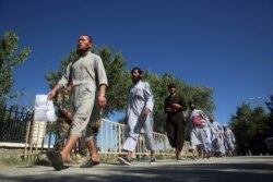 FILE - Afghan Taliban prisoners walk after being released from Bagram Prison, in Parwan province, Afghanistan, May 26, 2020.