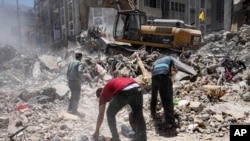 Construction equipment is used to sift through rubble before it is transported away from the scene of a building destroyed in an airstrike prior to a cease-fire that halted an 11-day war between Gaza's Hamas rulers and Israel, May 27, 2021, in Gaza City.