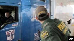 FILE - Border Patrol agent Eric Mendoza speaks to the driver of a tractor-trailer waiting to pass through the Laredo North vehicle checkpoint in Laredo, Texas, on Feb. 2, 2018.