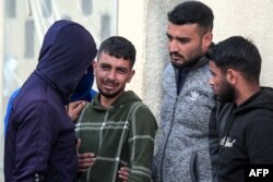 FILE —Palestinian men react at al-Aqsa hospital in Deir el-Balah as people mourn the death of loved ones killed during Israeli bombardment, in the central Gaza Strip, on March 6, 2024, amid ongoing battles between Israel and the militant group Hamas.