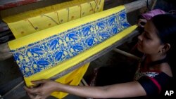 FILE - A member of the "hargila army," the name of the endangered Greater Adjutant Stork in local Assamese language, displays a weave with motifs of the bird in Dadara village, west of Gauhati, India. 