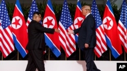 지난 2018년 6월 12일 싱가포르에서 열린 첫 미-북 정상회담에서 도널드 트럼프 미국 대통령과 김정은 북한 국무위원장이 악수를 하기 위해 서로에게 손을 내밀고 있다.