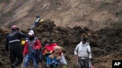 Residentes caminan en un área barrida por un deslizamiento de tierra en Alausí, Ecuador, el martes 28 de marzo de 2023, después de que una avalancha enterró decenas de casas y mató al menos a siete personas. 