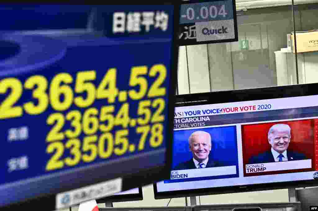 Una pantalla muestra los precios de las acciones de la Bolsa de Valores de Tokio como un canal de noticias que presenta retratos de los candidatos presidenciales de los EE.UU. Donald Trump y Joe Biden en una compa&#241;&#237;a de comercio de divisas en Tokio.