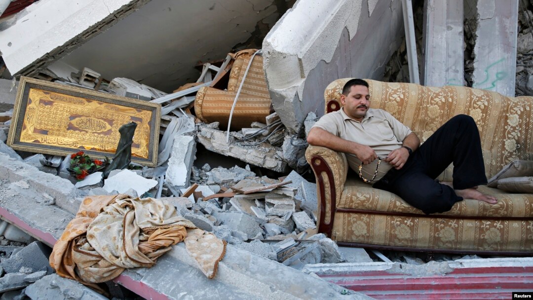 Seorang warga Palestina duduk di sofa di tengah reruntuhan rumahnya yang hancur di Gaza karena serangan Israel, 2014.