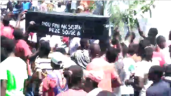 Protesters in Les Cayes march with a coffin with words that read "We are done with this repressive, predatory system".
