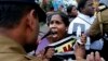 Sri Lankan policemen try to control ethnic Tamil people, whose relatives are missing, during a protest outside a public library where British Prime Minister David Cameron was meeting Tamil leaders, in Jaffna, northern Sri Lanka, Nov.15, 2013.