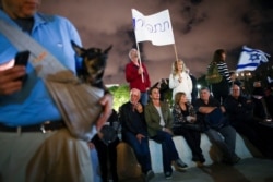 FILE - Protesters hold banners during a rally calling for the resignation of Israel's Prime Minister Benjamin Netanyahu, in Tel Aviv, Israel, Nov. 30, 2019. The Hebrew sign reads, "Resign."