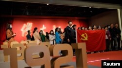 On April 22, 2021, in Beijing, people hold the Chinese national flag while posing for a group picture at an exhibition marking the centennial of the Chinese Communist Party, which falls on Thursday, July 1, 2021. Reuters/Thomas Peter