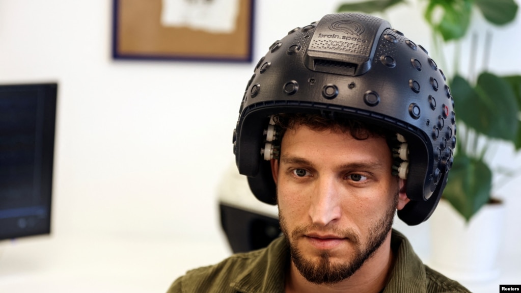 A worker at the Israeli startup Brain.Space shows an electroencephalogram (EEG) enabled helmet, due to be used in an experiment on the effects of a microgravity environment on the brain activity of astronauts, in Tel Aviv, Israel on March 23, 2022. (REUTERS/Nir Elias)