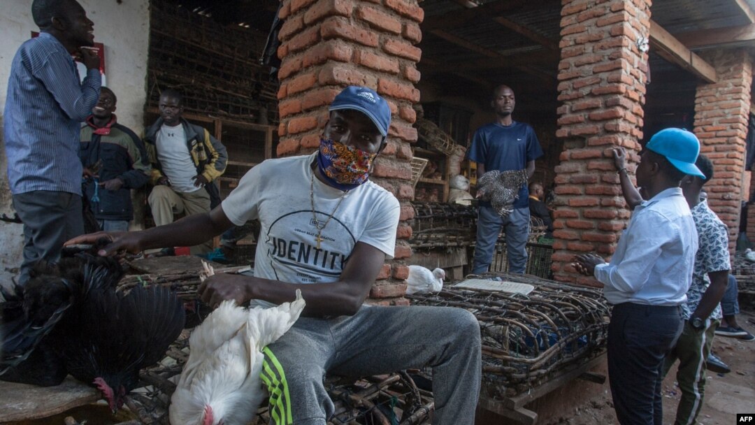 FILE - A vendor wears a face mask as a precaution against the coronavirus, as people around him do not, at the Lilongwe City market in Lilongwe, May 18, 2020. Malawi's government has vowed to crack down on COVID-19 prevention measures.