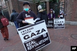 FILE - George Stevens, of Cambridge, Mass., front, hands out leaflets to passers-by near an entrance to Harvard University, Tuesday, Dec. 12, 2023, in Cambridge. (AP Photo/Steven Senne)