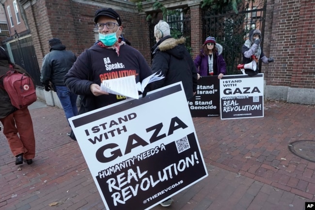 FILE - George Stevens, of Cambridge, Mass., front, hands out leaflets to passers-by near an entrance to Harvard University, Tuesday, Dec. 12, 2023, in Cambridge. (AP Photo/Steven Senne)