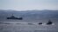 A rescue boat escorts a dinghy with migrants from Afghanistan as a Frontex vessel patrols in the background, on the island of Lesbos, Greece, February 28, 2020.
