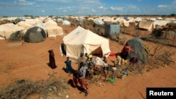 Refugees stand outside their tent at the Ifo Extension refugee camp in Dadaab, near the Kenya-Somalia border in Garissa County, Kenya on Oct. 19, 2011. 