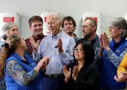 FILE - Former vice president and Democratic presidential candidate Joe Biden, center, is applauded as he speaks during a tour at the Plymouth Area Renewable Energy Initiative in Plymouth, N.H., June 4, 2019.