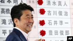 PM Jepang Shinzo Abe tersenyum saat berada di markas pemilu partainya di Tokyo, setelah pemilihan hari Minggu (21/7).