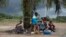 People suffering from the Ebola virus sit under a tree at Makeni Arab Holding Centre in Makeni, Sierra Leone, Oct. 4, 2014. 