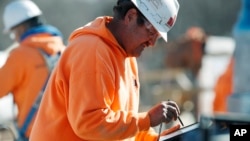 FILE - A worker programs a tablet to control SAM, a semi-automated mason, as it works on the facade of a school in the south Denver suburb of Englewood, Colorado, Feb. 27, 2018.