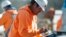 FILE - A worker programs a tablet to control SAM, a semi-automated mason, as it works on the facade of a school in the south Denver suburb of Englewood, Colorado, Feb. 27, 2018.