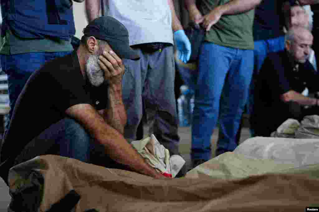 A mourner reacts near the bodies of people who were killed in an Israeli airstrike that destroyed the municipal headquarters in Nabatieh on Wednesday, during a collective funeral held for 13 people in Nabatieh, southern Lebanon.