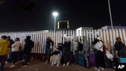 FILE - Migrants from Cuba and Venezuela line up at a Mexican immigration checkpoint as they make their way across the border for appointments to legally apply for asylum in the United States, Nov. 5, 2024, in Tijuana, Mexico.