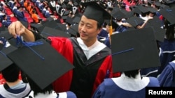 A man adjusts a student's mortar board during the graduation ceremony at Fudan University in Shanghai June 28, 2006. (File)