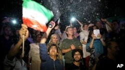 FILE - A group of jubilant Iranians cheer and spray artificial snow during street celebrations following the announcement of a landmark nuclear deal that meant the lifting of economic sanctions, in Tehran, July 14, 2015.