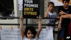 A girl holds a peace message during a peace protest at Ladras or Lokmachi crossing point that connects the Greek Cypriot south and the Turkish Cypriots breakaway north, inside the U.N buffer zone in central divided capital, Nicosia, Cyprus, July 6, 2017. 