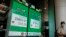 A man wearing a face mask walks past a bank electronic board showing the Hong Kong share index at Hong Kong Stock Exchange on May 14, 2020.