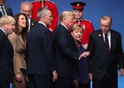 U.S. President Donald Trump, center left, speaks with German Chancellor Angela Merkel, center right, during a ceremony event at a NATO leaders meeting at The Grove hotel and resort in Watford, Hertfordshire, England, Dec. 4, 2019.