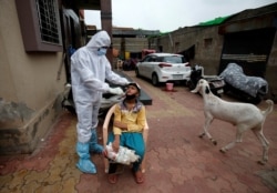 A health care worker wearing protective gear takes a swab from a boy for a rapid antigen test, amidst the coronavirus outbreak, at a residential area in Ahmedabad, India, July 24, 2020.