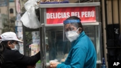 A woman buys a sandwich near the Clinical Studies Center of the Cayetano Heredia University, where volunteers lend themselves to test an experimental COVID-19 vaccine developed by the Chinese pharmaceutical Sinopharm, in Lima, Peru, Sept. 9, 2020.