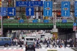 Commuters walk near Shinjuku Station in Tokyo on May 31, 2021 after the announcement that the government extended a coronavirus emergency in Tokyo and other parts of the country until just a month before the Olympics. (Photo by Kazuhiro NOGI / AFP)