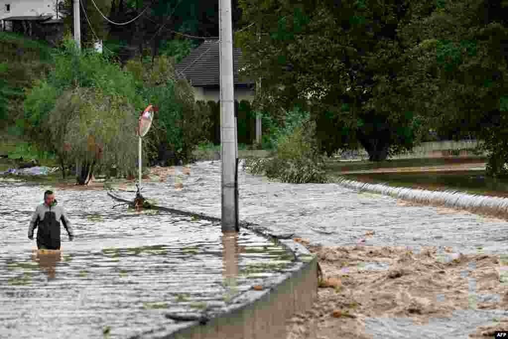 A man walks in the water along a flooded road following heavy rains in the town of Kiseljak, about 20 kilometers west of Sarajevo, Bosnia.