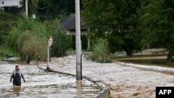 A man walks in the water along a flooded road following heavy rains in the town of Kiseljak, about 20 kilometers west of Sarajevo, Bosnia.