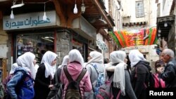 FILE - A group of school girls stand outside shops in the old city of Damascus, Syria, March 12, 2020.
