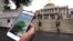 Seorang pemain Pokemon Go melihat ponselnya sambil berjalan melalui di luar gedung pemerintah di Boston, Massachusetts (18/7). (AP/Charles Krupa)