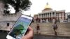 A Pokemon Go player consults his phone while walking through the Boston Common outside the Massachusetts Statehouse. The game has introduced players to some aspects of history they otherwise might have missed.