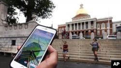 A Pokemon Go player consults his phone while walking through the Boston Common outside the Massachusetts Statehouse. The game has introduced players to some aspects of history they otherwise might have missed.