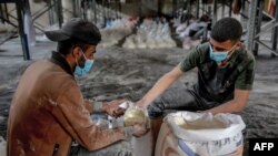 Para pekerja menjatah tepung yang akan diberikan kepada para warga di Kota Gaza sebagai bagian dari pendistribusian bantuan kemanusiaan pada 17 Maret 2024. (Foto: AFP)