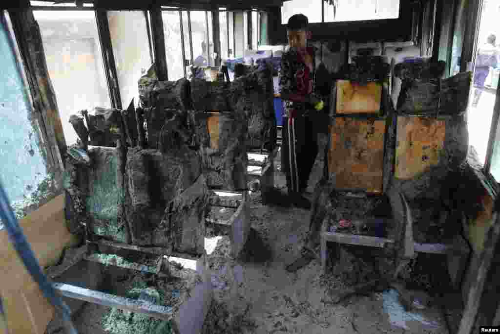 Seorang anak laki-laki memeriksa rongsokan sebuah bus yang hancur dibakar oleh para aktivis Partai Nasionalis Bangladesh (BNP), selama berlangsung aksi mogok di ibukota Dhaka. Bangladesh.