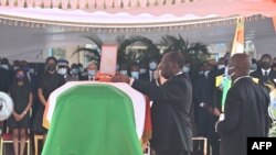 Le président ivoirien Alassane Ouattara (C) place une décoration sur le cercueil de feu le Premier ministre ivoirien Hamed Bakayoko lors de sa cérémonie d'hommage officielle le 17 mars 2021.