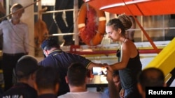 FILE - Carola Rackete, the 31-year-old Sea-Watch 3 captain, is escorted off the ship by police and taken away for questioning, in Lampedusa, Italy, June 29, 2019. (Reuters) 