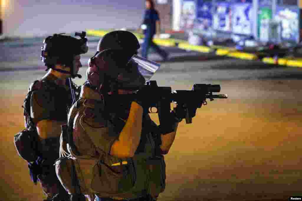 Police officers defend the scene for firefighters to work after looting at the Dellwood Market in Ferguson, Missouri, Aug. 17, 2014.